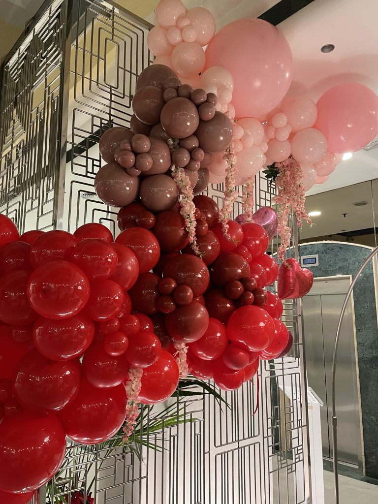 globos en color rojo, buredos y rosa, formando una guirnalda orgánica para decorar un hotel en San Valentín 